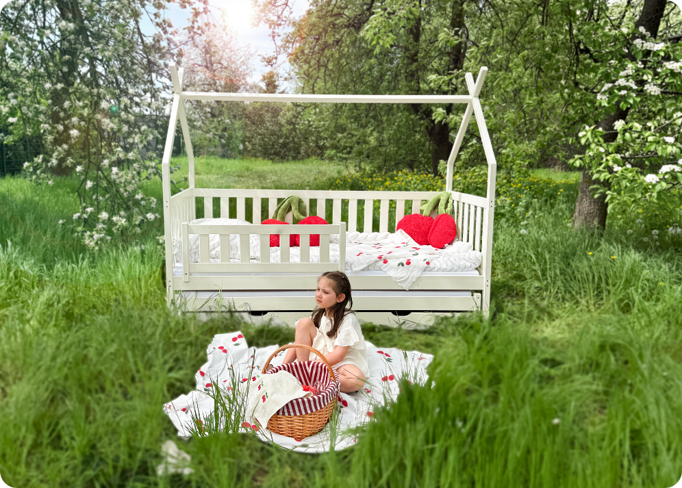 A girl sitting outdoors in a beautiful meadow setting in front of a cotton bed shaped like a tipi house